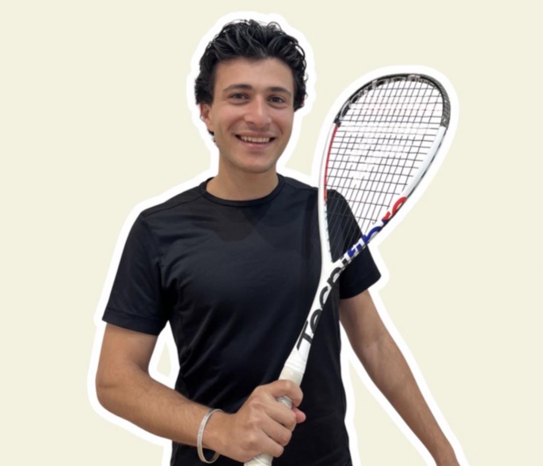 Coach Ezz holding a squash racquet